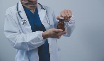 sudeste ásia médico médico segurando uma garrafa do pílulas, sorridente isolado branco fundo foto