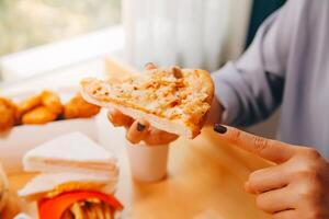 cortada imagem do mulher segurando pizza fatia às restaurante foto