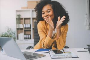 foto do bonita jovem menina sentar Área de Trabalho pc aguarde caneta escrever bloco de anotações vestem óculos camisa dentro casa escritório dentro de casa