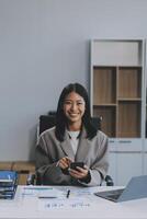 empresário de felicidade bela jovem asiática de negócios usar celular de uso casual para compras on-line desfrutar com mídia social e laptop em casa startup de pequenas empresas online banking foto