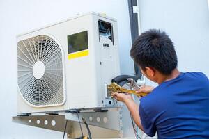 masculino técnico instalando ao ar livre unidade do ar condicionador para legal a família dentro a verão. ar compressor, eletrônico, quente verão, Alto temperatura, tropical países foto