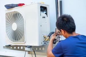 masculino técnico instalando ao ar livre unidade do ar condicionador para legal a família dentro a verão. ar compressor, eletrônico, quente verão, Alto temperatura, tropical países foto