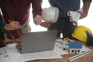 engenheiros estão consultando a equipe para Projeto a arquitetônico estrutura para clientes com plantas e construção modelos para trabalhos às escritório. foto