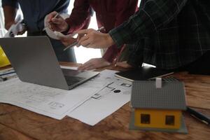 engenheiros estão consultando a equipe para Projeto a arquitetônico estrutura para clientes com plantas e construção modelos para trabalhos às escritório. foto