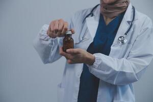 sudeste ásia médico médico segurando uma garrafa do pílulas, sorridente isolado branco fundo foto