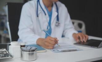 uma profissional e focado ásia fêmea médico dentro esfrega é trabalhando e lendo médico pesquisa em dela computador portátil dentro dela escritório às uma hospital. foto