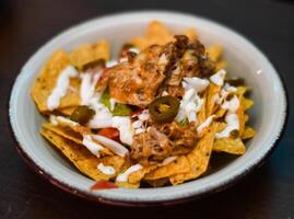 servindo do nachos com carne, queijo, branco molho e Jalapenos foto