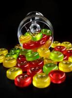 uma muitos do doce bengalas estão espalhados a partir de a derrubado vidro cálice. multicolorido doces dentro uma vidro em uma Preto fundo. foto