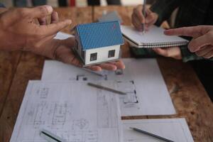 engenheiros estão consultando a equipe para Projeto a arquitetônico estrutura para clientes com plantas e construção modelos para trabalhos às escritório. foto