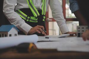 conceito de construção e estrutura de reunião de engenheiro ou arquiteto para projeto trabalhando com parceiros e ferramentas de engenharia na construção de modelo e projeto no local de trabalho, contrato para ambas as empresas. foto