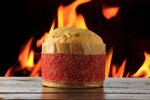 panetone, comida decorativa, mesa de madeira, fogo ao fundo foto