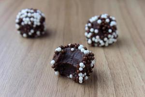 brigadeiro, brigadeiro, chocolate doce típico da culinária brasileira coberto por partículas, em fundo de madeira. foto