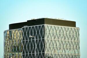 vidro construção com transparente fachada do a construção e azul céu. estrutural vidro parede refletindo azul céu. abstrato moderno arquitetura fragmento. contemporâneo arquitetônico fundo. foto