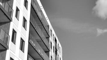 fragmento do a edifício de fachada com janelas e varandas. moderno apartamento edifícios em uma ensolarado dia. fachada do uma moderno residencial prédio. Preto e branco. foto