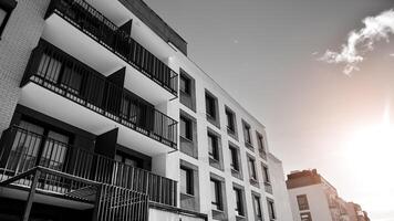 fragmento do a edifício de fachada com janelas e varandas. moderno apartamento edifícios em uma ensolarado dia. fachada do uma moderno residencial prédio. Preto e branco. foto