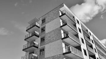 fragmento do a edifício de fachada com janelas e varandas. moderno apartamento edifícios em uma ensolarado dia. fachada do uma moderno residencial prédio. Preto e branco. foto