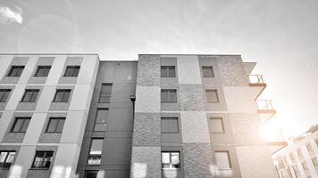 fragmento do a edifício de fachada com janelas e varandas. moderno apartamento edifícios em uma ensolarado dia. fachada do uma moderno residencial prédio. Preto e branco. foto