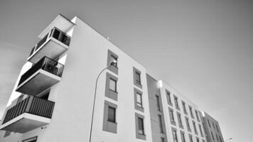 fragmento do a edifício de fachada com janelas e varandas. moderno apartamento edifícios em uma ensolarado dia. fachada do uma moderno residencial prédio. Preto e branco. foto