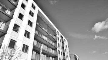 fragmento do a edifício de fachada com janelas e varandas. moderno apartamento edifícios em uma ensolarado dia. fachada do uma moderno residencial prédio. Preto e branco. foto