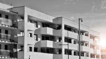 fragmento do a edifício de fachada com janelas e varandas. moderno apartamento edifícios em uma ensolarado dia. fachada do uma moderno residencial prédio. Preto e branco. foto