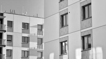 fragmento do a edifício de fachada com janelas e varandas. moderno apartamento edifícios em uma ensolarado dia. fachada do uma moderno residencial prédio. Preto e branco. foto