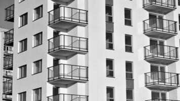 fragmento do a edifício de fachada com janelas e varandas. moderno apartamento edifícios em uma ensolarado dia. fachada do uma moderno residencial prédio. Preto e branco. foto