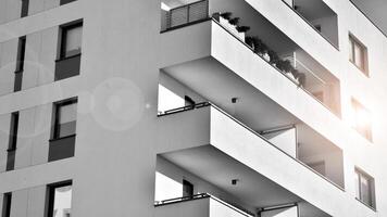 fragmento do a edifício de fachada com janelas e varandas. moderno apartamento edifícios em uma ensolarado dia. fachada do uma moderno residencial prédio. Preto e branco. foto