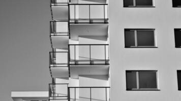 fragmento do a edifício de fachada com janelas e varandas. moderno apartamento edifícios em uma ensolarado dia. fachada do uma moderno residencial prédio. Preto e branco. foto