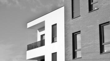 fragmento do a edifício de fachada com janelas e varandas. moderno apartamento edifícios em uma ensolarado dia. fachada do uma moderno residencial prédio. Preto e branco. foto