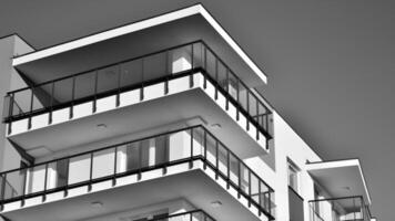 fragmento do a edifício de fachada com janelas e varandas. moderno apartamento edifícios em uma ensolarado dia. fachada do uma moderno residencial prédio. Preto e branco. foto