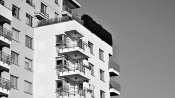 fragmento do a edifício de fachada com janelas e varandas. moderno apartamento edifícios em uma ensolarado dia. fachada do uma moderno residencial prédio. Preto e branco. foto