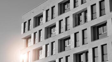 fragmento do a edifício de fachada com janelas e varandas. moderno apartamento edifícios em uma ensolarado dia. fachada do uma moderno residencial prédio. Preto e branco. foto