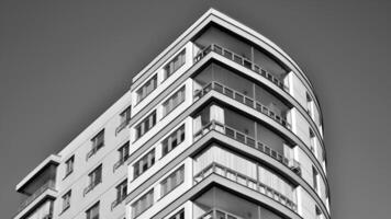 fragmento do a edifício de fachada com janelas e varandas. moderno apartamento edifícios em uma ensolarado dia. fachada do uma moderno residencial prédio. Preto e branco. foto