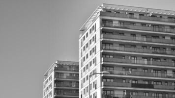 fragmento do a edifício de fachada com janelas e varandas. moderno apartamento edifícios em uma ensolarado dia. fachada do uma moderno residencial prédio. Preto e branco. foto