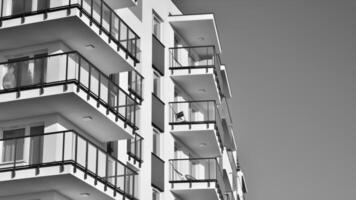 fragmento do a edifício de fachada com janelas e varandas. moderno apartamento edifícios em uma ensolarado dia. fachada do uma moderno residencial prédio. Preto e branco. foto