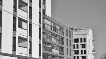 fragmento do a edifício de fachada com janelas e varandas. moderno apartamento edifícios em uma ensolarado dia. fachada do uma moderno residencial prédio. Preto e branco. foto