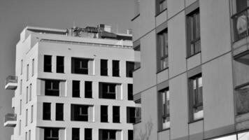 fragmento do a edifício de fachada com janelas e varandas. moderno apartamento edifícios em uma ensolarado dia. fachada do uma moderno residencial prédio. Preto e branco. foto