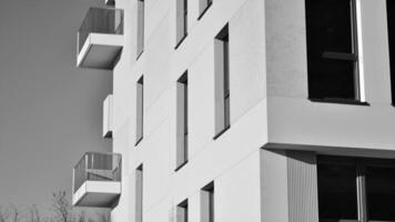 fragmento do a edifício de fachada com janelas e varandas. moderno apartamento edifícios em uma ensolarado dia. fachada do uma moderno residencial prédio. Preto e branco. foto