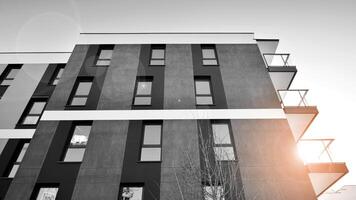 fragmento do a edifício de fachada com janelas e varandas. moderno apartamento edifícios em uma ensolarado dia. fachada do uma moderno residencial prédio. Preto e branco. foto