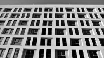 fragmento do a edifício de fachada com janelas e varandas. moderno apartamento edifícios em uma ensolarado dia. fachada do uma moderno residencial prédio. Preto e branco. foto