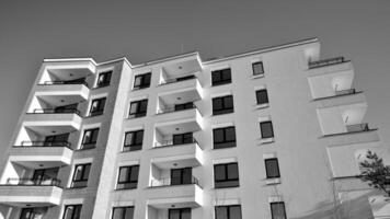 fragmento do a edifício de fachada com janelas e varandas. moderno apartamento edifícios em uma ensolarado dia. fachada do uma moderno residencial prédio. Preto e branco. foto