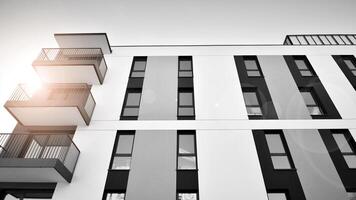 fragmento do a edifício de fachada com janelas e varandas. moderno apartamento edifícios em uma ensolarado dia. fachada do uma moderno residencial prédio. Preto e branco. foto