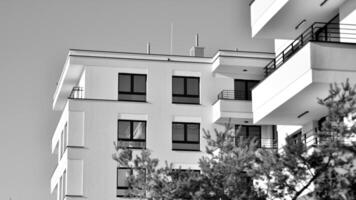 fragmento do a edifício de fachada com janelas e varandas. moderno apartamento edifícios em uma ensolarado dia. fachada do uma moderno residencial prédio. Preto e branco. foto