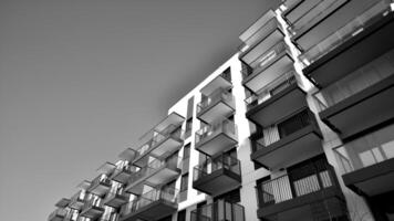 fragmento do a edifício de fachada com janelas e varandas. moderno apartamento edifícios em uma ensolarado dia. fachada do uma moderno residencial prédio. Preto e branco. foto