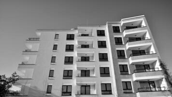 fragmento do a edifício de fachada com janelas e varandas. moderno apartamento edifícios em uma ensolarado dia. fachada do uma moderno residencial prédio. Preto e branco. foto