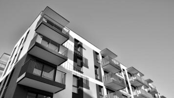 fragmento do a edifício de fachada com janelas e varandas. moderno apartamento edifícios em uma ensolarado dia. fachada do uma moderno residencial prédio. Preto e branco. foto