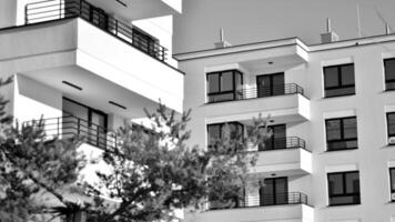 fragmento do a edifício de fachada com janelas e varandas. moderno apartamento edifícios em uma ensolarado dia. fachada do uma moderno residencial prédio. Preto e branco. foto