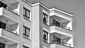 fragmento do a edifício de fachada com janelas e varandas. moderno apartamento edifícios em uma ensolarado dia. fachada do uma moderno residencial prédio. Preto e branco. foto