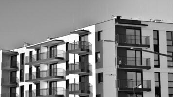 fragmento do a edifício de fachada com janelas e varandas. moderno apartamento edifícios em uma ensolarado dia. fachada do uma moderno residencial prédio. Preto e branco. foto