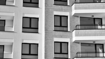 fragmento do a edifício de fachada com janelas e varandas. moderno apartamento edifícios em uma ensolarado dia. fachada do uma moderno residencial prédio. Preto e branco. foto